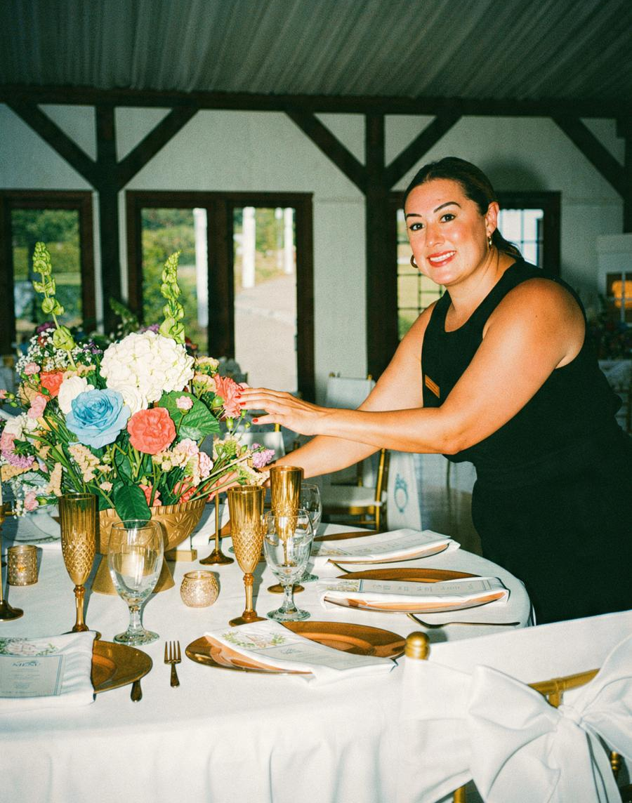 Norma Jaramillo styling a reception table with florals and gold place settings