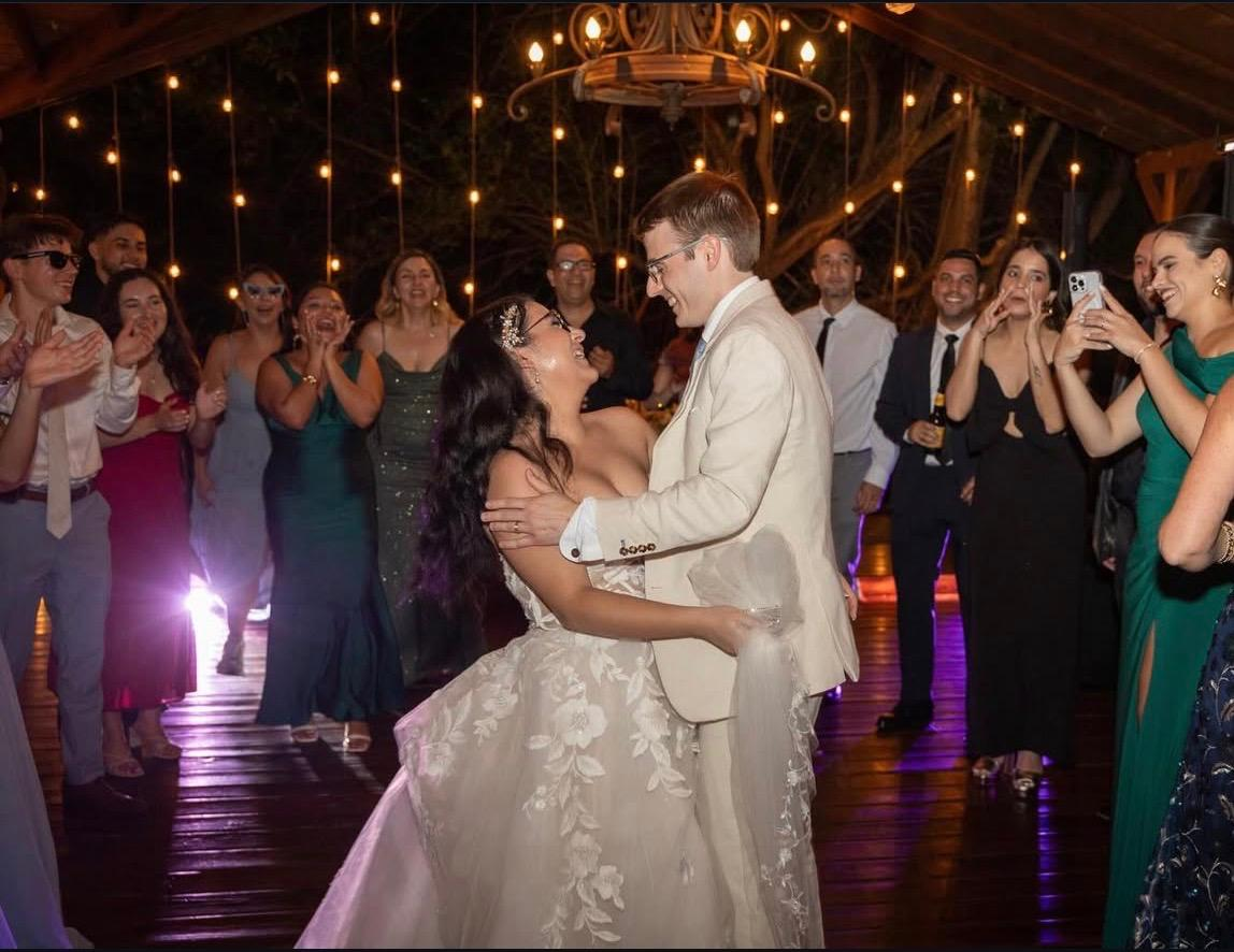 Couple dancing at a candlelit wedding reception surrounded by guests