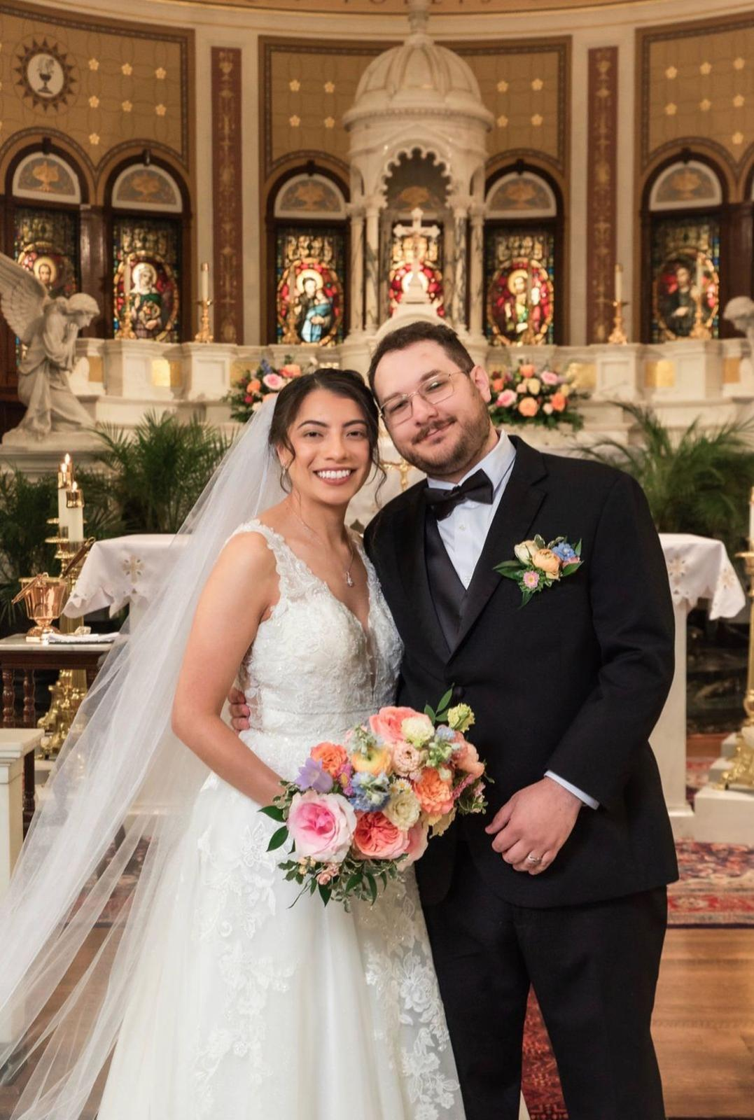 Bride and groom at their church ceremony holding a colorful bouquet